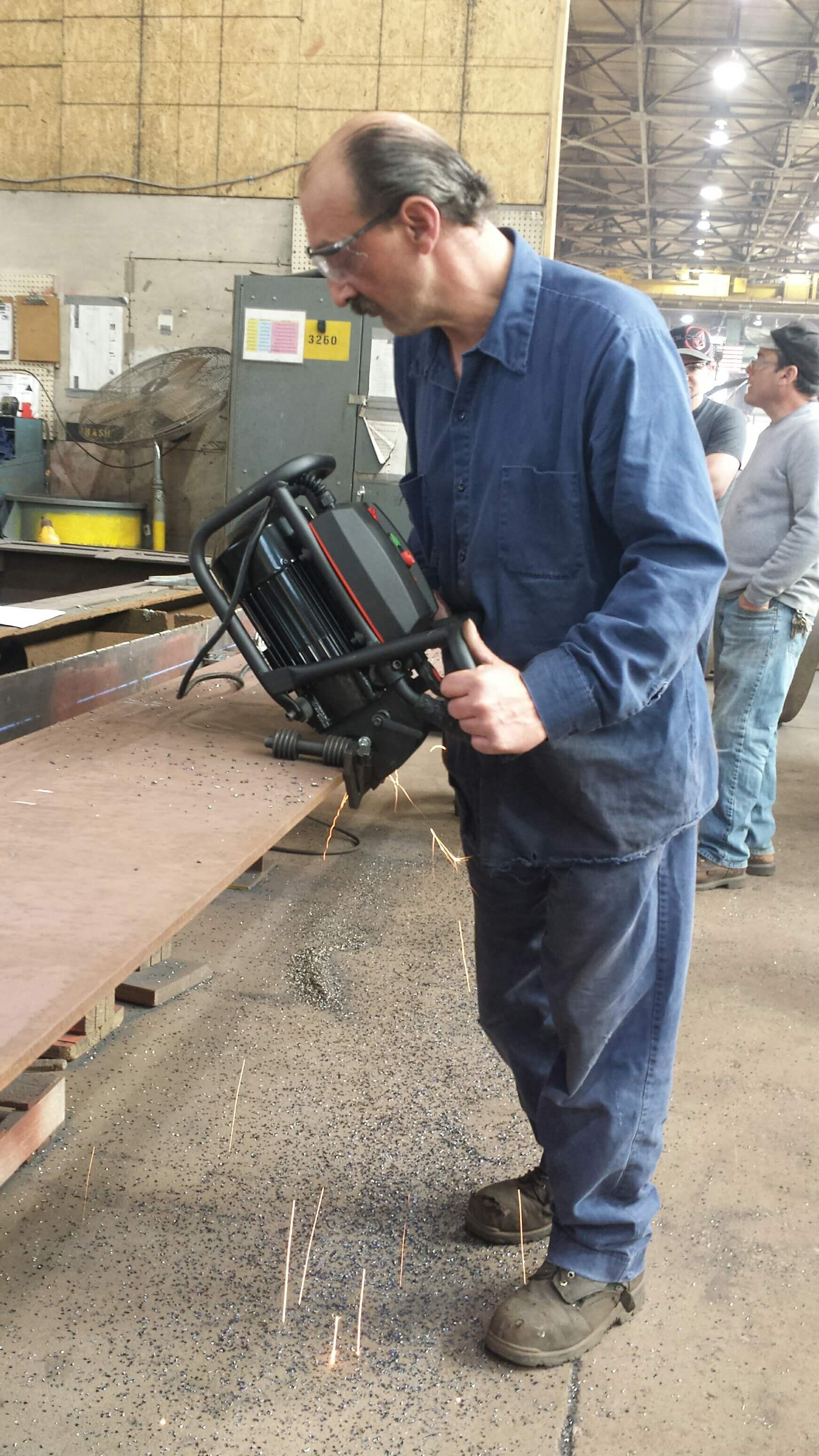 factory worker using a handheld metal grinder